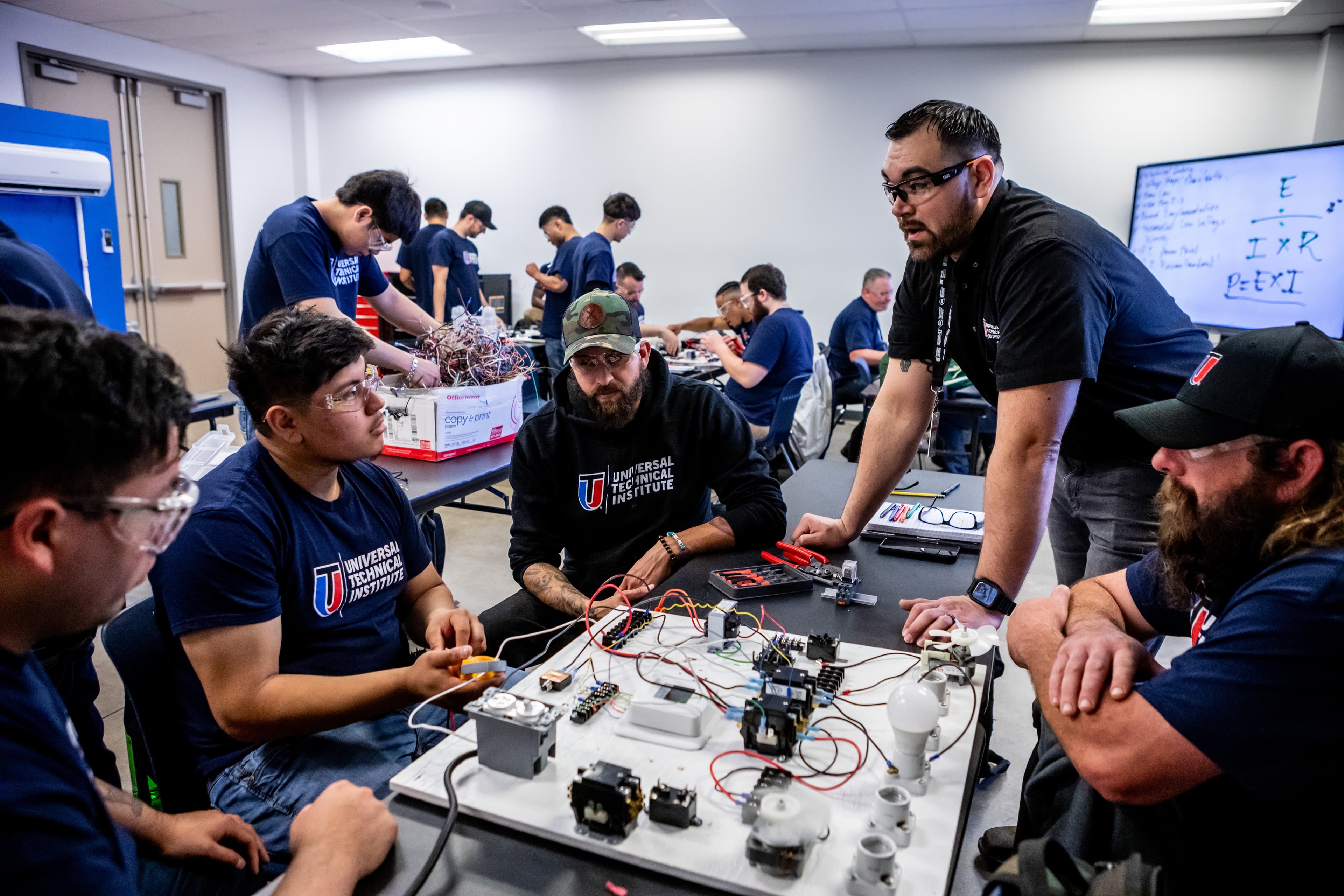 HVAC trade school students and an instructor working with electrical training boards during a hands-on technical class.