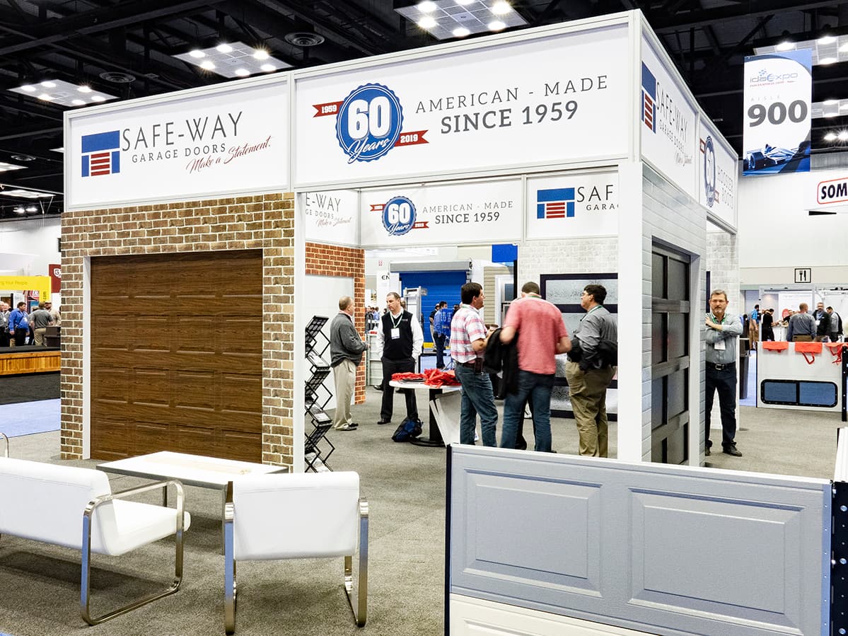Safe-Way Garage Doors booth at an industry trade show with full-size overhead door displays and American-made branding.