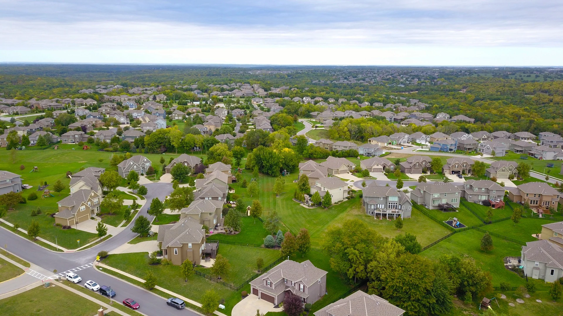 A wide aerial view of residential streets, houses and trees.