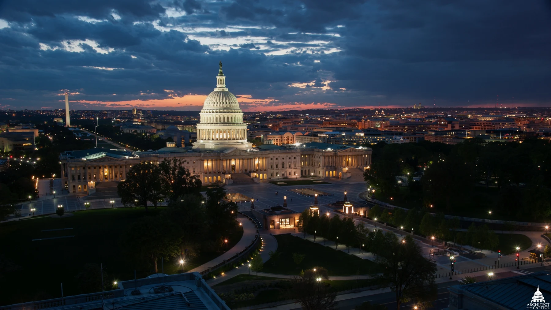 The illuminated U.S. Capitol beneath a cloudy evening sky, viewed from the Library of Congress.
